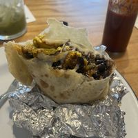 Beso del Chorizo burrito is packed with tofu scramble, potatoes, green chile, vegan cheese, jackfruit chorizo, beans, and finished with a rich cashew crema, onions, cilantro, and a at Hoja in Denver