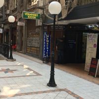When you pass through the archway, you will see this interior square with streetlights and a green and yellow sign. The kiosk is in an archway beside the sign. at Veganski Kiosk in Belgrade