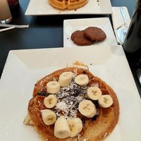 Front to back: full size waffle with coconut, Oreo crumble, and bananas, plant based sausage patties, and half waffle with strawberries and candied nuts. at Waffles INCaffeinated - Fifth Ave in Pittsburgh