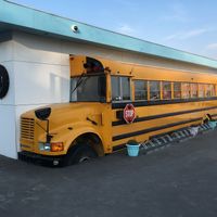 An old american school bus on the side of the building. You can sit inside the bus on the inside.  at Stacy's Diner in Koege