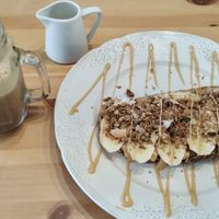 Banana toast with granola and peanut butter with an iced coffee on the side. at Bali Food & Drinks in Leiria