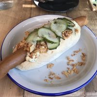 Vegan hot dog with remoulade, picked cucumber and crispy onions at Lion's Den in Haslemere