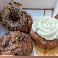 Apple fritter bottom left, ferrero rocher top left, cinnamon bun doughnut at Machino Donuts - Bloor St in Toronto