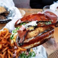 Dude Ranch Fried seitan chikun patty topped with ranch, bacun, lettuce, and tomato served on a pretzel bun. at Seitan's Realm in Columbus