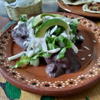 Several tortillas smothered in a black bean sauce at Aguacate Limon in Tulum