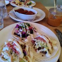 Three different vegan tacos with vegan "wings" in the background at The Burrow in Vancouver