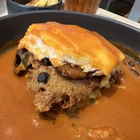 Showing the hearty filling of the Francesinha style Portuguese Sandwich (vegan). Shredded seitan, Beyond Meat Sausage, mushrooms, tomato in bread covered in Francesinha toppings.  at Kind Kitchen in Porto