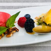 Raspberry sorbet, mango sorbet on caramelized peanuts, almond slivers and pistachios. Decorated with fresh berries at MythenForum in Schwyz