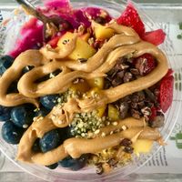 Sweet sunset bowl. Base: dragon fruit, banana, strawberry, pineapple, oranges. Toppings: strawberries, mango, blueberries, cacao nibs, hemp seeds, PB drizzle at Green Culture in New Port Richey