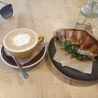 Tempeh croissant and different cats on each cappuccino. at Rohe in Tallinn