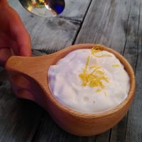 Yummy vegan plum desert with caramelised sugar, crisp and whipped cream and lemon cest on top - served in a traditional wooden cup. at Jazzköket in Ostersund