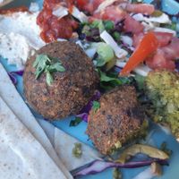 Amazing juicy, tasty green falafel on a plate with hummus, vegetables and dressings. at Falavela in Crete