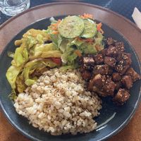 Sticky sesame tofu with brown rice, salad and vegetables in a small dish   at Gosto Superior in Braga