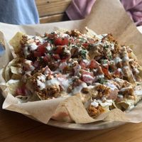 nachos - tortilla chips, cauliflower chorizo, cheese sauce, refried beans, pico de gallo, jalapeño aioli and cilantro   at Watercourse Foods in Denver