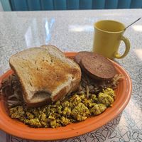 Vegan classic with sourdough toast, veggie sausage, hash browns, and the tofu scram. Coffee with oatmilk in the background. at Hartland Diner  in Hartland