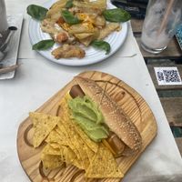 ‘Scrambled’ eggs and fried potatoes, and vegan cheese, guacamole hot dog  at Veganitessen in Sevilla