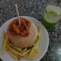 Hambúrguer com anéis de cebola, batata frita e suco verde. at Taberna 32 in Porto Alegre
