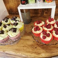 On the left are chocolate cupcakes with peppermint icing and mint chocolate on top, on the right are vanilla cupcakes with a raspberry jam centre, vanilla frosting and raspberries  at Not Just Desserts in Mansfield