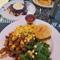 Half stack of blueberry pancakes, chicken biscuit with home fries, kale, and tofu scramble, and chicken and waffles at Cafe Sunflower in Atlanta
