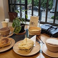 Um canto do café com algumas opções do cardápio: queijo quente, foccacia e pão pizza, além de um chocolate quente e outro café at Mona Café in Belo Horizonte