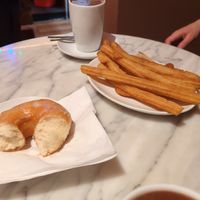 Hot chocolate with oat milk, part of the donut, and 6 churros. at The Vegan Corner in Barcelona