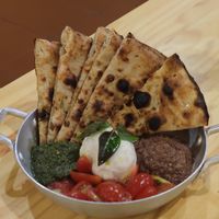 Porção de crostini servido com burrata, tomate cereja, tapenade, pesto de manjericão at Pizza Youth in Sao Paulo