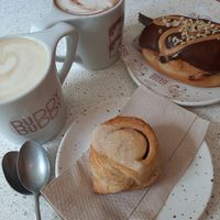 Drinks: The Buddy and Praline Chocolate, Food: Vegan Cinnamon Roll and Peanut Butter Donut at Buddy Buddy in Brussels