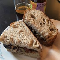 Mushroom and dry tomato sandwich, kombucha in the background at Odete Bakery in Porto