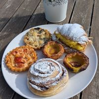 Two types of quiche, pastel de nata, Berliner, and a cinnamon roll. at Odete Bakery in Porto