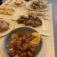 Orange chicken (front right), side of brown rice (left), seaweed quinoa roles (right), dumplings (right, 5 total) spring rolls (left), pad see ew with chicken (right back). at Salaya in Los Angeles