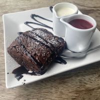 Hazelnut chocolate brownie with vegan cream and raspberry coulis   at Tywarnhayle Inn in Perranporth