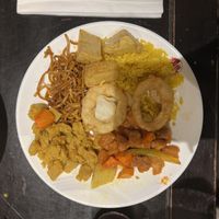 Platter of noodles, fried rice, crispy potatoes, chicken curry, sweet & sour chicken, mixed vegetables and onion rings at Su Vegan Buffet in West London