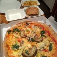 vegan pizza, burger and fries in the background at Urban Pizza in Vienna