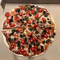 Pizza Gourmet con pesto, alcachofa, tomates cherry, salsa macha, cebolla morada y aceitunas at Goji in Saltillo