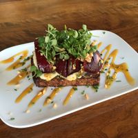 Seared stone fruit bruschetta with herbed macadamia cheese, golden balsamic reduction, hazelnuts, micro basil. at Encuentro in Oakland