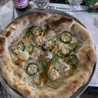 Pizza with chickpea base, courgette, courgette flowers, vegan mozzarella and toasted almonds  at Pepe Bianco in Salo