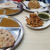 From bottom left, clockwise: aloo parantha, plain chapati, fried rice, mixed rice with sambal tofu, mutton curry and chickpeas and mixed pakoras (center) at Veg Chat in Kuala Lumpur