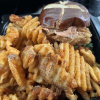 Fried chicken sandwich on a pretzel roll and waffle cut fries  at A Peace of Soul in Columbia