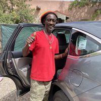 Ras putting a Happy Cow decal on his car  at Ras Rody's Jamaican Vegan  in Santa Fe