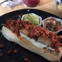 hecho en pan de levadura madre, salchicha vegana a base de soya, pepinillos. Acompañado de aguacate y pico de gallo  at Dulcinea Café Vintage in Cali