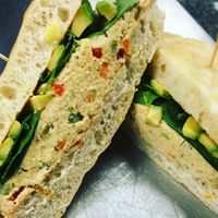 Vegan Hummus Salad sandwich comes topped with fresh spinach and avocado.  Served on house-made pretzel focaccia! at Pretzel & Pizza Creations in Frederick