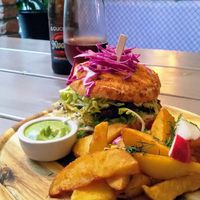A bbq-burger with potato wedges, and kvass in the background at Kozy Eats  in Riga
