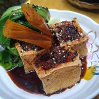 Fried tofu filled with savoury mushrooms, on a sweet soy sauce and steamed Pak choi at Ong Tao Vegan in Frankfurt
