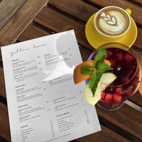 A copy of the menu with a soy milk flat white and sangria cocktail at Yellow Lane Cafe in Bangkok