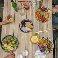 Hummus + grilled veggies (vegan) at top, salat with goat cheese (veggie) on the left, right corner "bowl" dish. 2 delicious juices and slow. beer at Gostilna Vida in Ljubljana