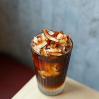 Iced coconut long black. Made with fresh coconut water, coconut flesh, topped with fresh organic espresso and garnished with homemade toasted coconut flakes. at Pimp My Salad in Bangkok