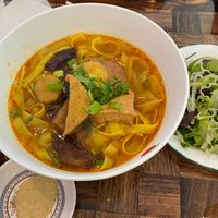 Mi Quang - yellow noodles with tofu, vegan meat, and purple potato.  The condiments are mixed herbs and greens.  Garnish wit crushed peanuts and rice crackers.   at Song Huong Vegetarian Restaurant in Duluth