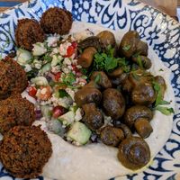 Hummus bowl topped with falafel balls, tabouli and Yemeni-style mushrooms.  at Mazel Tov in Budapest