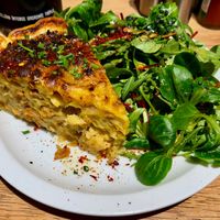 Quiche with cauliflower, caramelized onions en vegan bacon, served with a green salad € 12 (January 2026) at Lucifer Lives in Brussels