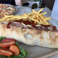 Vegan hot dog, vegan pizza in the background.  at Alkionis Sports Bar & Grill in Rhodes
